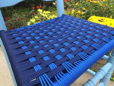 a blue plastic chair sitting in front of some flowers