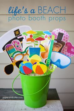 a green bucket filled with lots of assorted beach related items on top of a wooden table