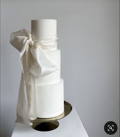 a three tiered white wedding cake with a bow on top