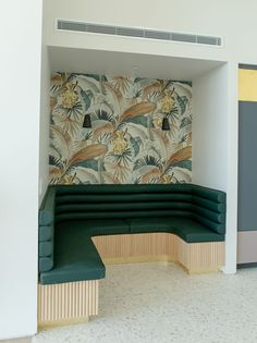 a green bench sitting in front of a wall with flowers on it