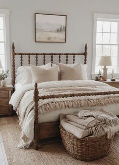 a large bed sitting next to two windows and a basket on top of the bed