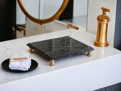 a bathroom counter with a marble tray and gold faucet