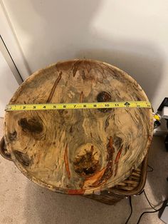 a wooden table with a measuring tape on it next to a white wall and floor