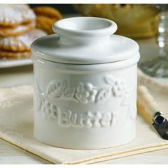 a white cookie jar sitting on top of a table next to cookies and silverware