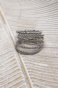 Image shows the Misha Silver Ring Set stacked laying a beige background. Silver Stackable Metal Midi Rings, Modern Twist Silver Stackable Midi Rings, Silver Stackable Midi Rings With A Modern Twist, Adjustable Stacked Silver Rings, Silver Stackable Double Band, Adjustable Stackable Silver Bands, Silver Stackable Double Band Midi Rings, Silver Stackable Midi Rings With Double Band, Silver Bands