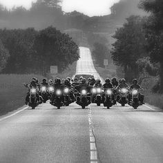 a group of motorcycles driving down the road in front of some people on their bikes