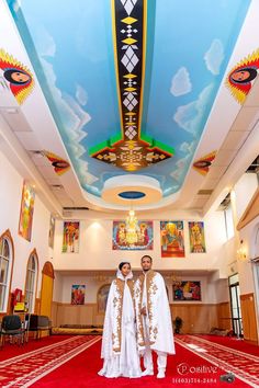 two people standing in front of a ceiling with paintings on the walls and ceilings above them