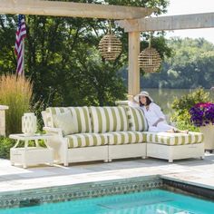 a woman sitting on top of a couch next to a swimming pool in a backyard