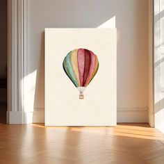 a painting of a hot air balloon in pastel colors on a white wall with wood flooring