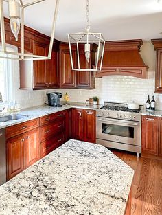 a kitchen with marble counter tops and wooden cabinets, along with stainless steel appliances in the center