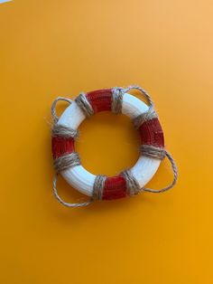 a red and white life preserver sitting on top of a yellow surface