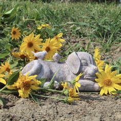 a small elephant laying on top of a field of yellow flowers