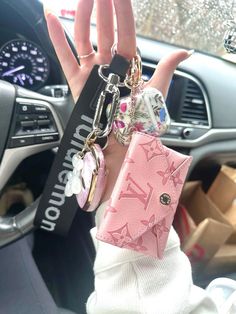 a person holding up two key chains in their hand while sitting in a car with other items