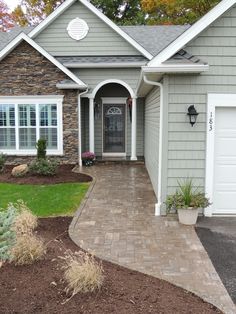 a house that has a driveway in front of it and landscaping around the entrance to the home