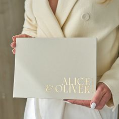 a woman holding a book with the words alice and oliver written in gold on it