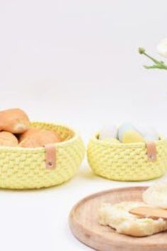 two yellow baskets filled with food next to a white vase and flowers on a table