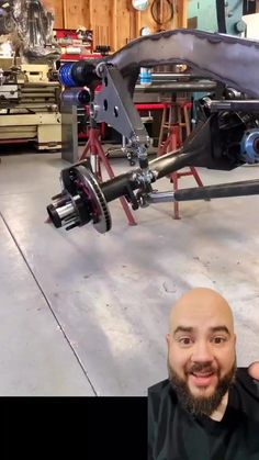 a bald man in a black shirt standing next to a car with an engine on it