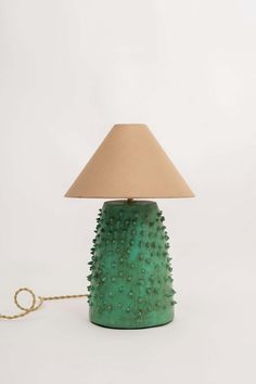 a green table lamp sitting on top of a white floor next to a light brown shade