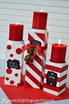 three red candles sitting next to each other on top of a table covered in christmas decorations