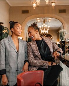 two women sitting next to each other in front of a bar with chandeliers hanging from the ceiling