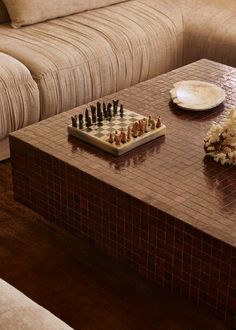 a living room with a couch, coffee table and chess board on the coffee table