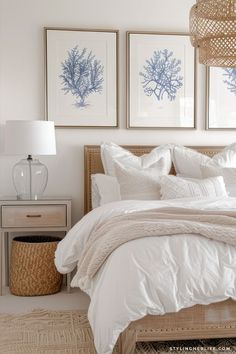 a bed with white sheets and pillows in a bedroom next to two pictures on the wall