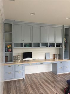 an office with gray cabinets and wooden floors