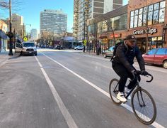 a man riding a bike down the middle of a street in front of tall buildings