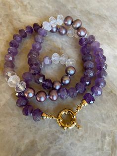 "Jammy shades of purple including Amethyst gemstones, Pearl and, Natural Quartz have been hand knotted on silk to create this one of a kind ombre necklace. A \"sailor\" bolt clasp in 24 karat gold overlay allows charms and pendants to be swapped on and off with ease. Wonderful to wear alone, layered or styled with your favorite medals and charms. The necklace measures approximately 20\" inches end to end and, the gemstones are approximately 8mm. Some stretching will naturally occur with knotted Purple Gemstones, Ombre Necklace, Candy Necklace, Silk Jewelry, Candy Necklaces, Stackable Bangles, Necklace Purple, 24 Karat Gold, Gold Overlay