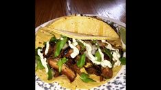 two tacos on a plate topped with meat and greens