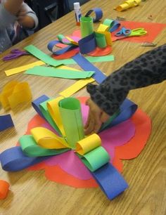 the child is playing with construction paper on the table