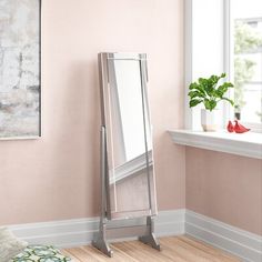 a mirror is leaning against the wall next to a window in a room with pink walls