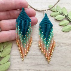 a pair of blue and orange beaded earrings sitting on top of a wooden table