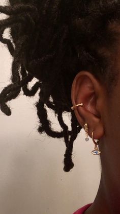 a close up of a person with dreadlocks wearing earring and pink shirt