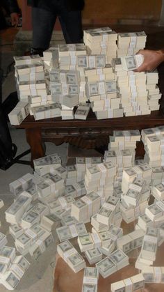 stacks of money are piled on top of each other in front of a wooden bench