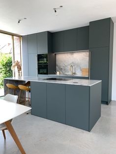 a modern kitchen with grey cabinets and marble counter tops is seen in this image from the dining room