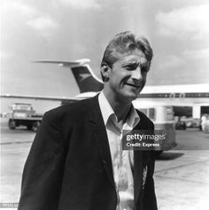 an old black and white photo of a man standing in front of an airplane on the tarmac