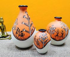 three orange and white vases sitting on top of a table next to a gold statue