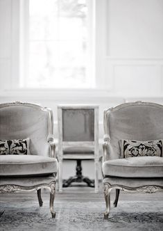 two chairs sitting next to each other in front of a window