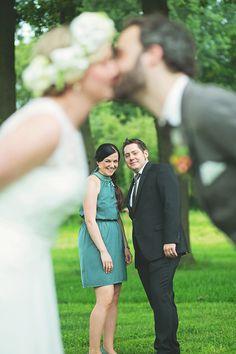 a man and woman standing next to each other in front of trees with their faces close together