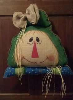 a green pillow with a smiling face on it's side hanging from a wooden door