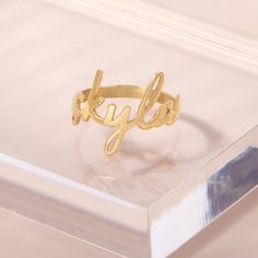 A fun new way to wear the nameplate style! The Nella Nameplate Ring is custom made with your choice of text in a sweet, lowercase script. This delicate, unique ring is available in rose gold, gold, or rhodium-plated sterling silver for a completely personalized piece. Available in sterling silver, 18k gold or 18k rose gold plated sterling silver Band width: 2mm Name height approximately 1/4" (varies with characters) Protected with an anti-tarnish barrier This is a lowercase only font, uppercase Trendy Personalized Adjustable Rings, Trendy Personalized Open Ring, Custom Name Adjustable Initial Ring In 14k Gold, Adjustable 14k Gold Initial Ring With Custom Name, Trendy Personalized Gold Rings, Trendy Personalized Rings For Promise, Minimalist Custom Name Engraved Ring In Rose Gold, Trendy Personalized Promise Ring, Minimalist Rose Gold Engraved Ring With Custom Name