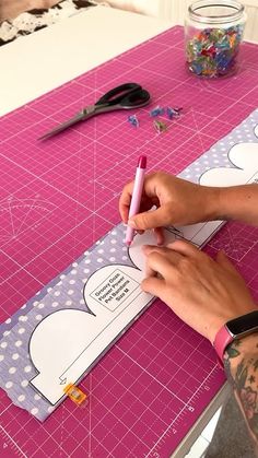 a person is making a cutout for a craft project on a pink cutting mat