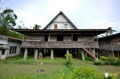 an old wooden house sitting in the middle of a lush green field