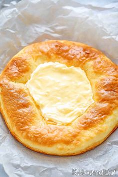 a baked pastry with butter on top sits on wax paper and looks like it is ready to be eaten