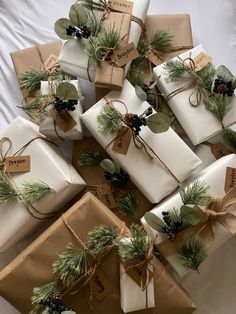 many wrapped presents are stacked on top of each other with evergreen leaves and pine cones