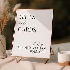 a white sign sitting on top of a table next to a vase filled with flowers