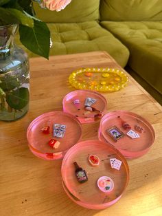 three pink plates on a table next to a vase with flowers and beads in it