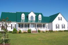 a large white house with green roof and windows