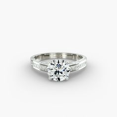 a white gold engagement ring with diamonds on the band and a round brilliant center stone